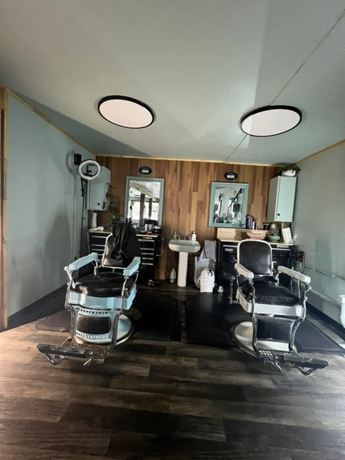 A styling room inside Barber Shack in Bellingham — vintage chairs, mirrors, a ring light, and a wood accent wall.