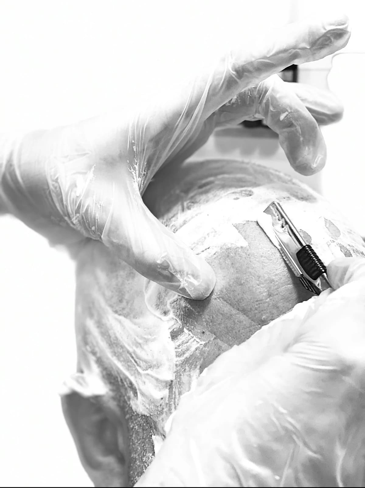 A straight razor taken over the scalp in high-key black and white.