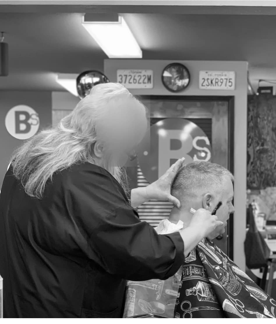 A shave underway on the shop floor at Barber Shack, in black and white.
