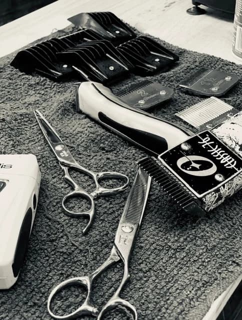 Barbering tools laid out on the towel — shears, clippers, and a straight razor.