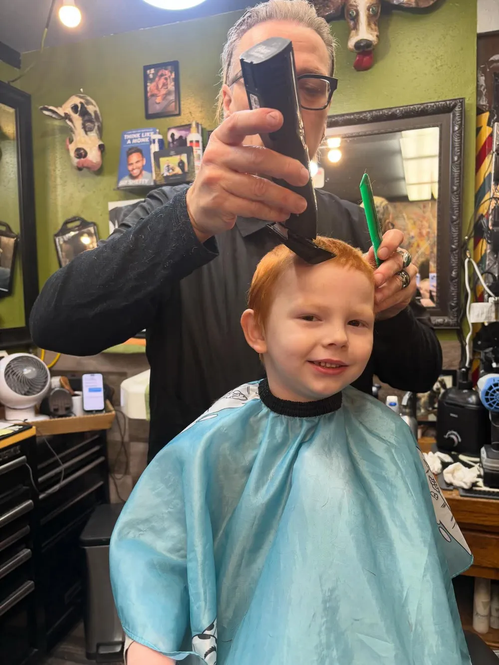A young client smiling through a kids' cut at Barber Shack.
